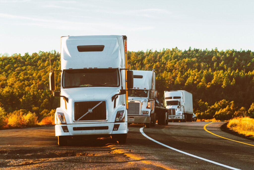 18-Wheeler Accident Claims in Nevada | Marathon Law Group 1 Several white semi trucks driving on a highway with scenic background, representing transportation law, commercial trucking regulations, logistics legal services, and road safety compliance in the legal industry. © Marathon Law Group