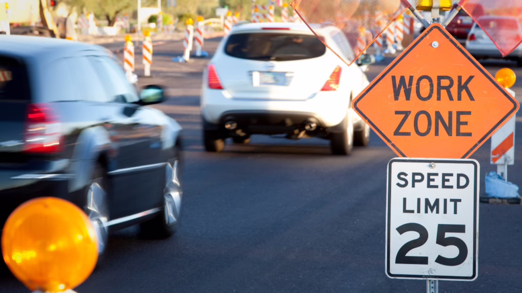 Las Vegas Construction Zone Accident Attorney: I-15 and US-95 Work Zone Crashes 1 Cars driving through a road work zone with an orange "WORK ZONE" sign and a "SPEED LIMIT 25" sign visible in the foreground. © Marathon Law Group